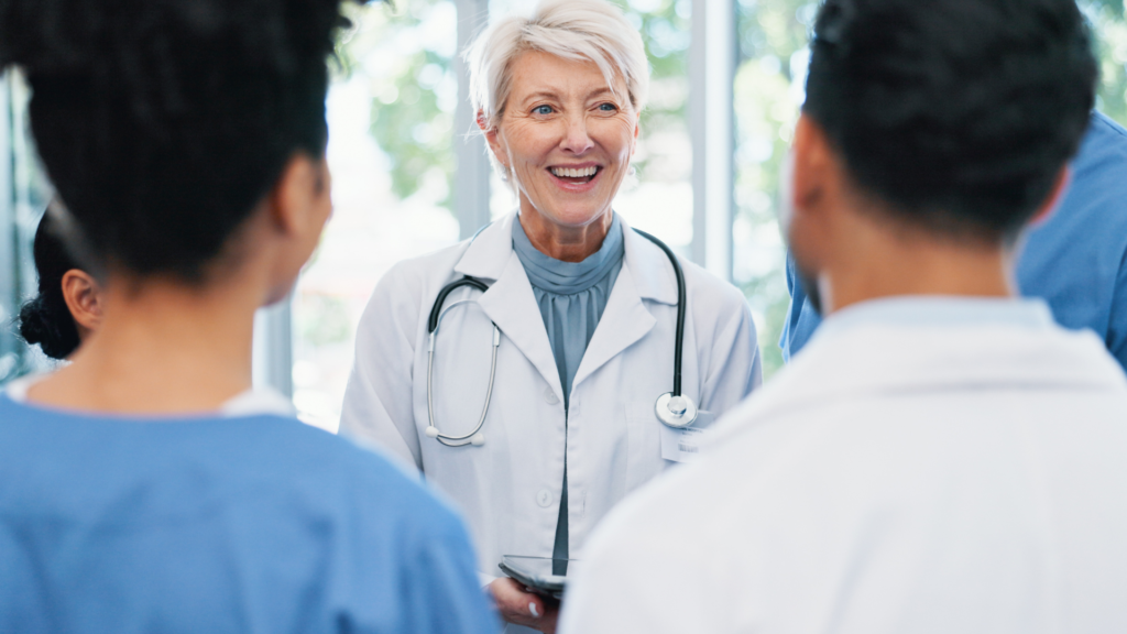 Een foto van een vrouwelijke dokter die andere dokters toespreekt.